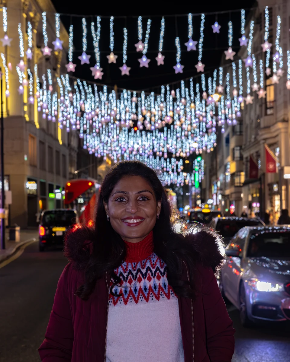 Matty on Oxford Street beneath rows of Christmas lights.