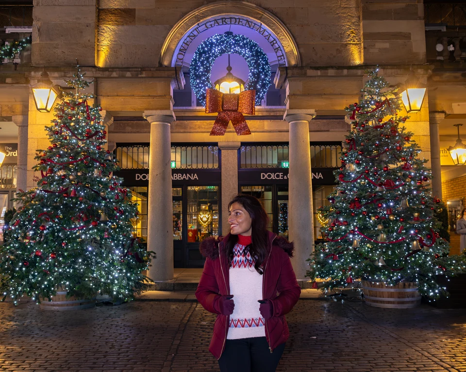 Matty between Christmas trees beneath the illuminated wreath outside Covent Garden Market.
